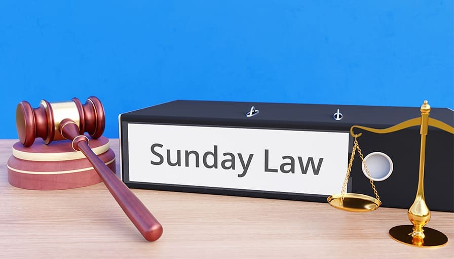 A binder labeled “Sunday Law” placed on a desk beside a judge’s gavel and a golden balance scale.